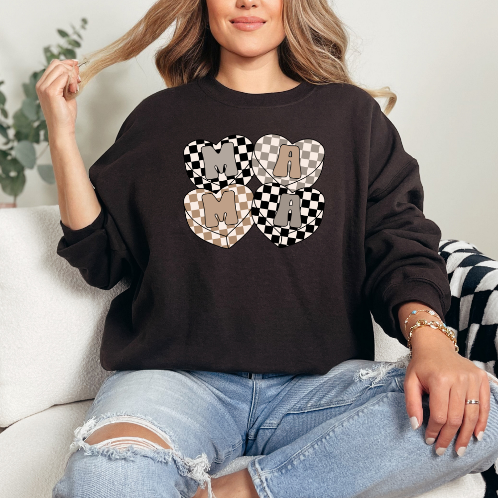 Mama checkered hearts 4 hearts with single letters inside spelling MAMA neutral checkered background in gray black and caramel in each heart containing single letter. Hearts overlap slightly in center creating beautiful design. Sweater color dark chocolate brown.