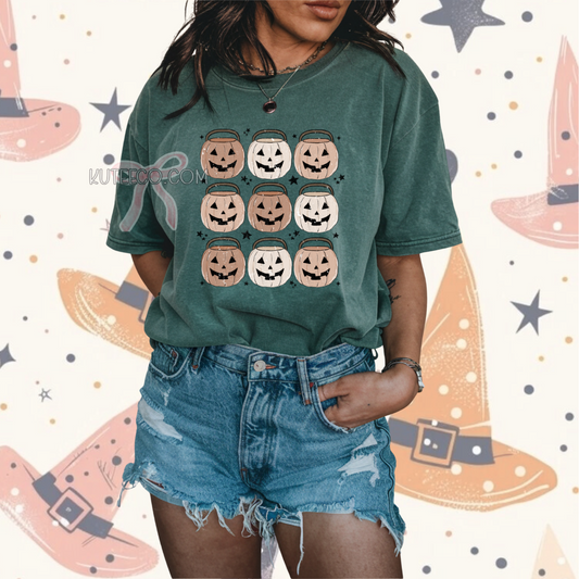 Person wearing a cool toned green t-shirt with Halloween-themed design, jack o lantern pumpkin bucket 9 in rows  with dainty black stars around as accents.